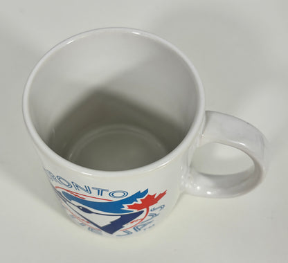 A white ceramic coffee mug featuring the Toronto Blue Jays logo and team name printed on the side, shown from an overhead angle on a plain white background.