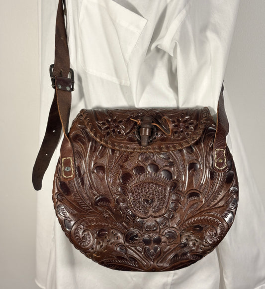 Brown leather bag with intricate patterns on a white background