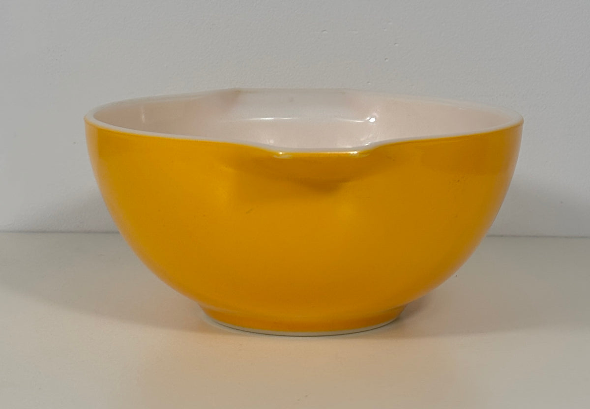 A bright yellow bowl with a white interior, photographed against a plain light gray background.
