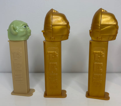 Three gold and green character figures on stands against a white background