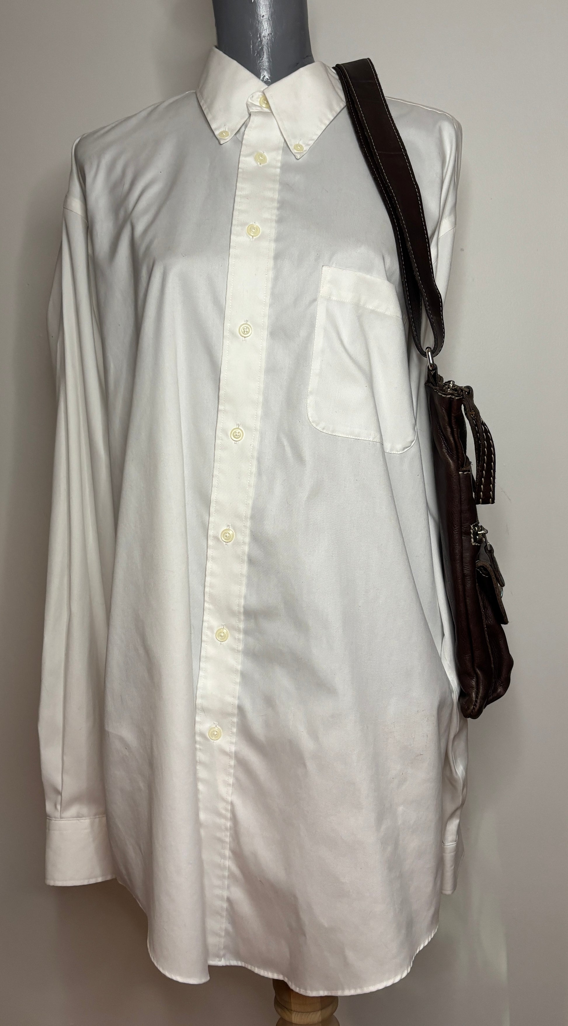 White dress shirt on a mannequin with a black bag over the shoulder against a gray background