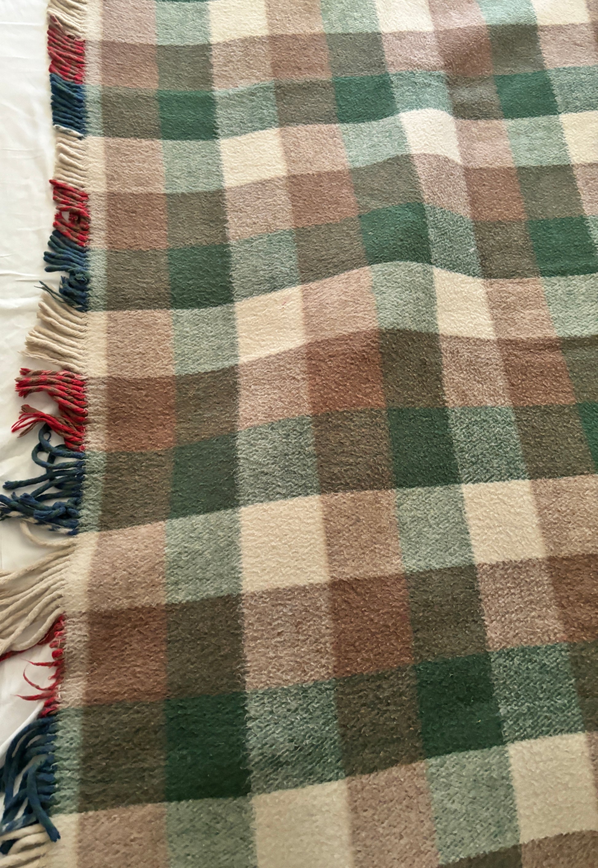 Plaid blanket with brown, green, and beige colors on a white background