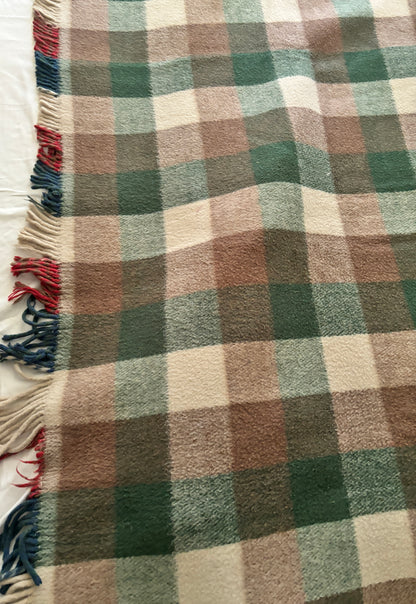 Plaid blanket with brown, green, and beige colors on a white background