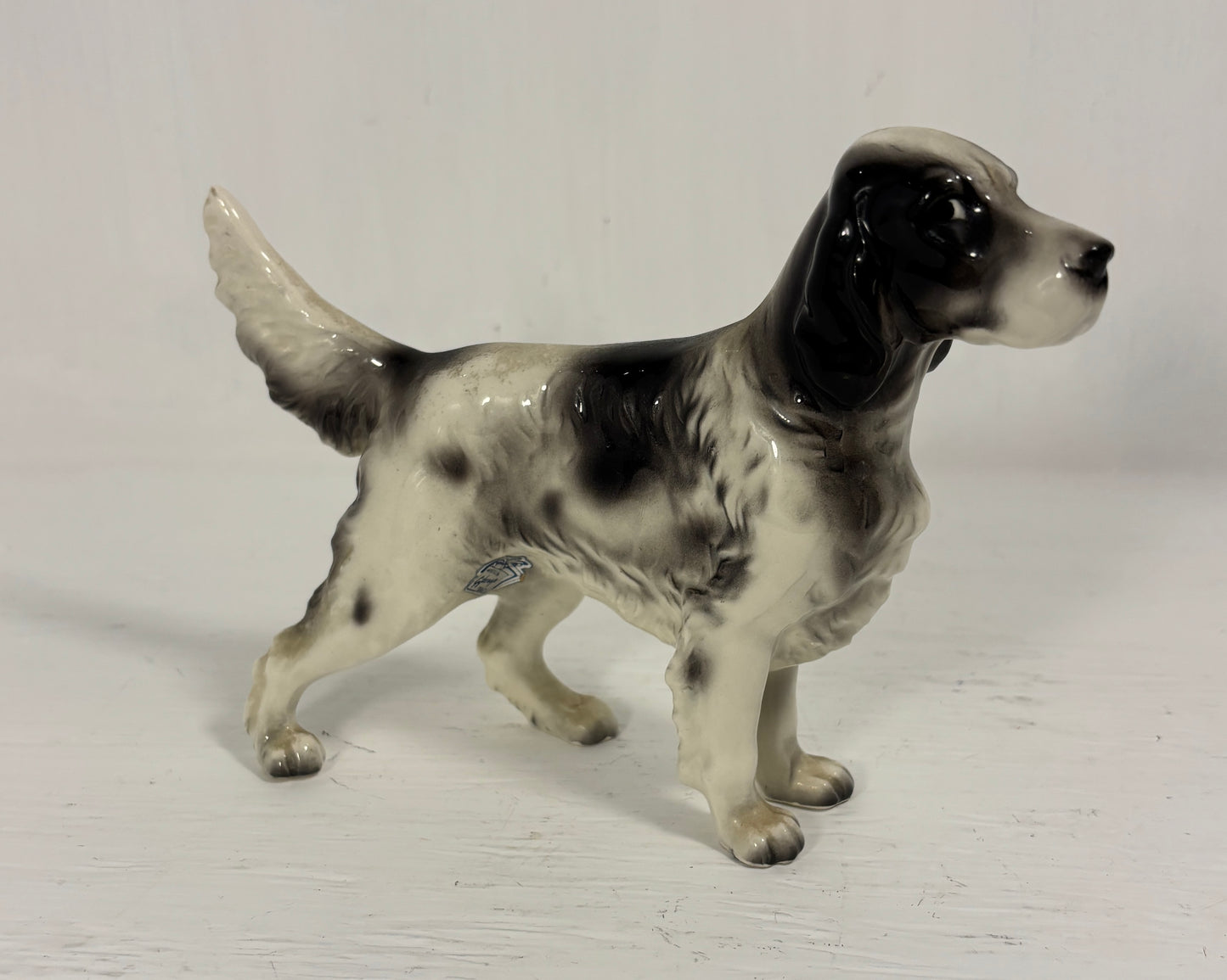 Dog figurine with black and white pattern on a light gray background