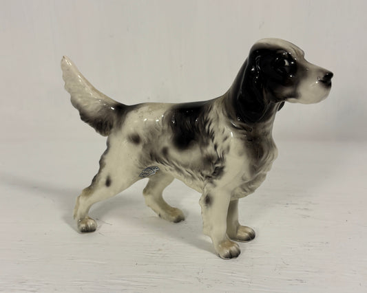 Dog figurine with black and white pattern on a light gray background