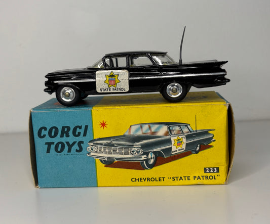 Model car of a Chevrolet State Patrol on top of its box, with 'Corgi Toys' branding.