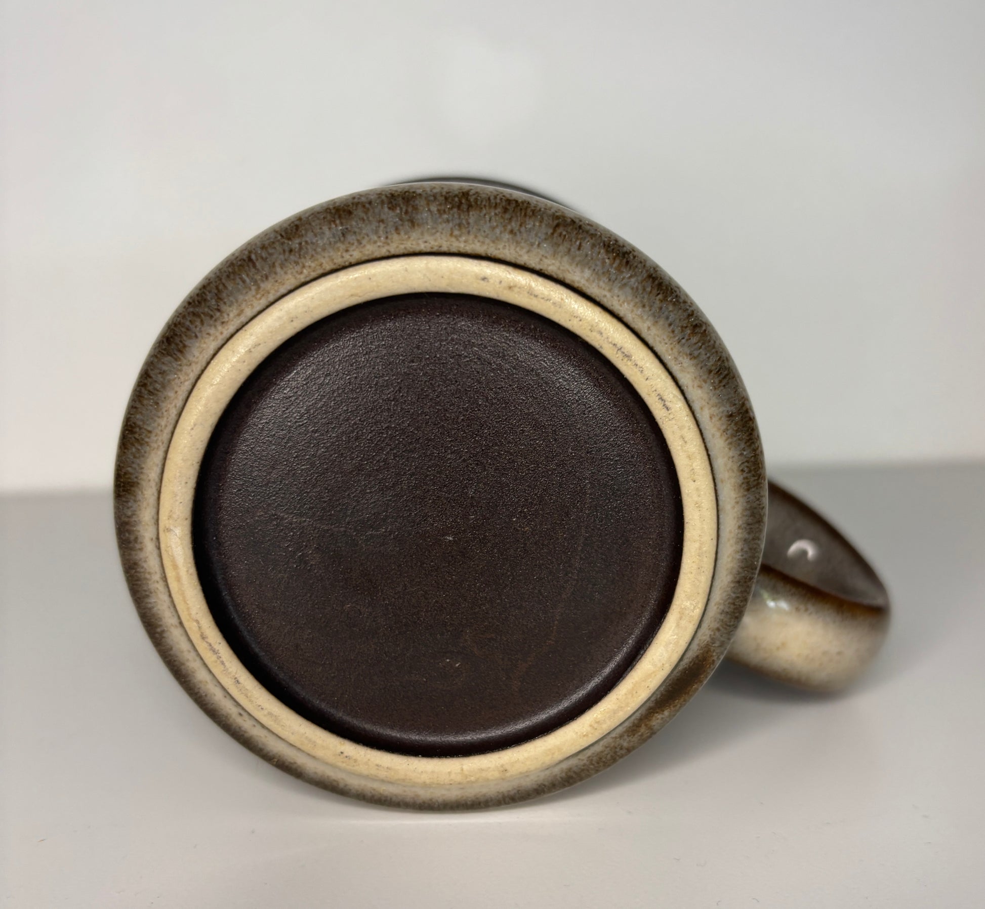 Close-up of a ceramic mug with a dark brown interior on a light gray background