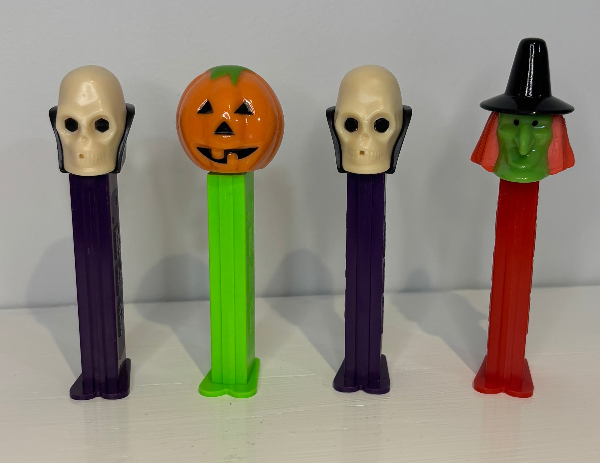 Four Halloween-themed PEZ dispensers on a white surface with a gray background
