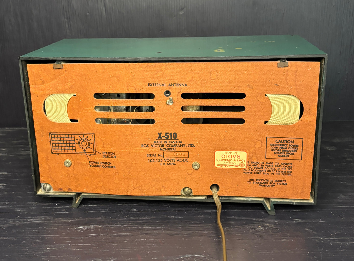 Vintage radio with brown front panel and green top on a dark background