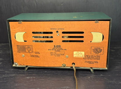 Vintage radio with brown front panel and green top on a dark background