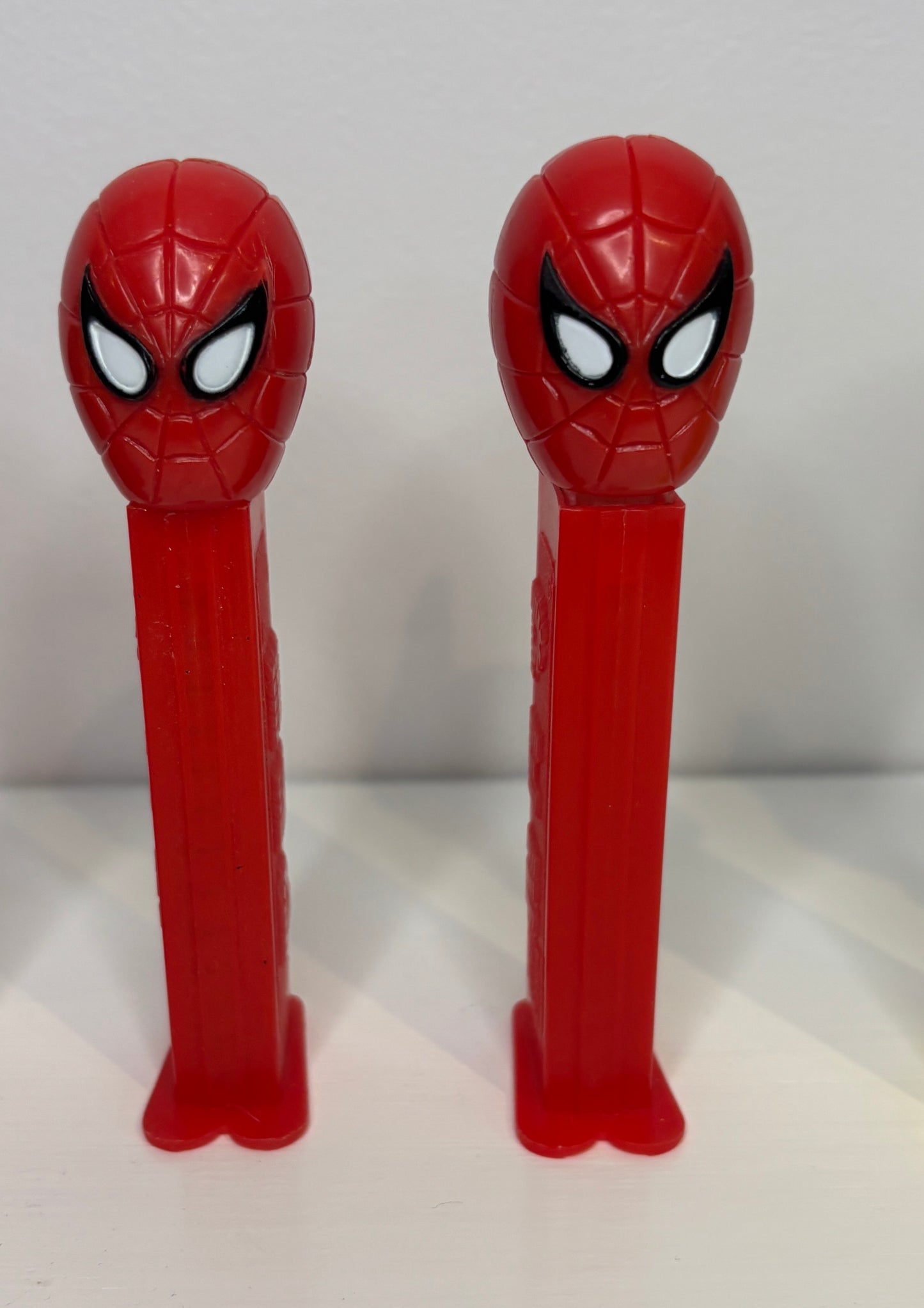 Two red Spider-Man PEZ dispensers on a white background