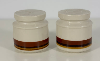 Two ceramic salt and pepper shakers with brown bands on a white background