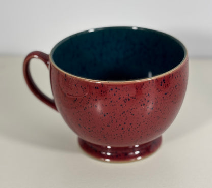 Speckled red and green ceramic mug on a white background