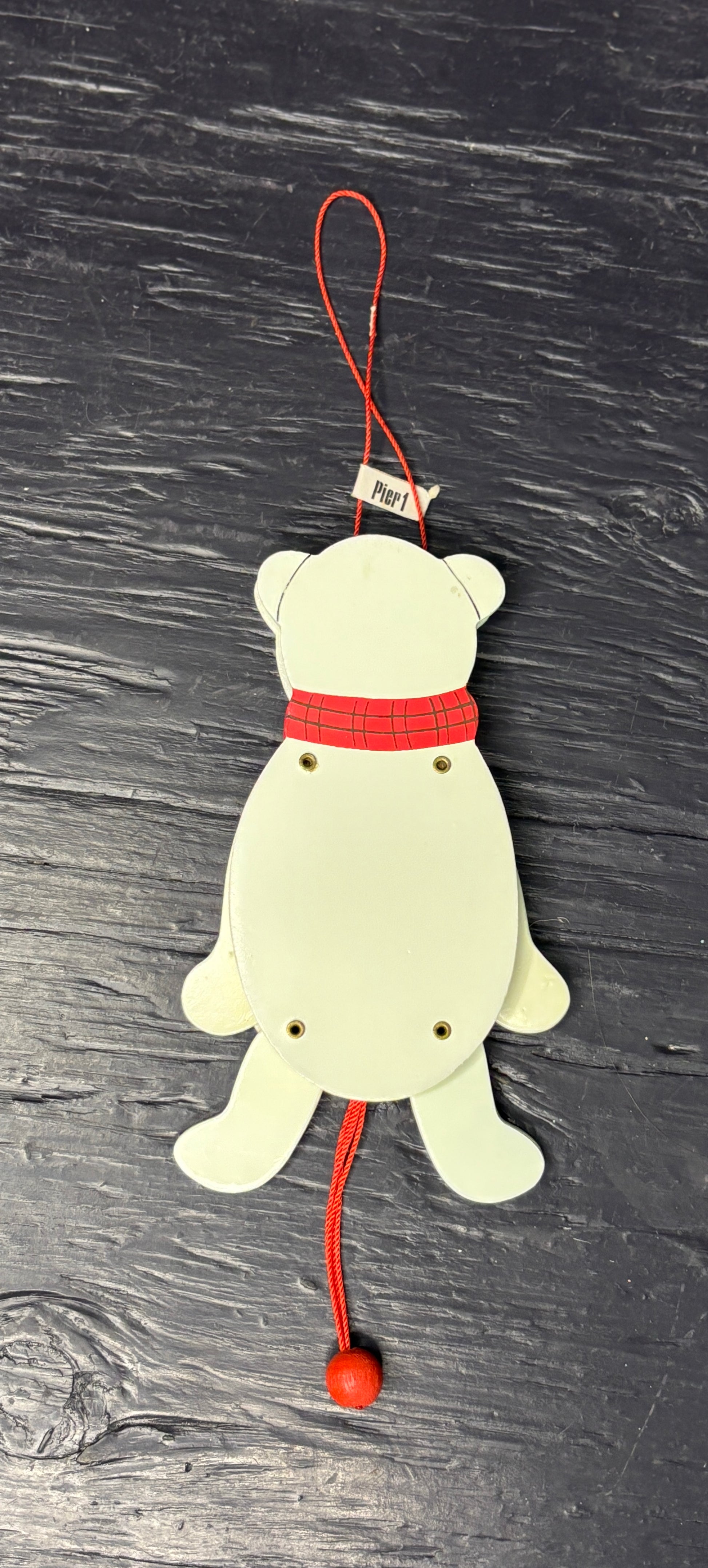 White bear-shaped ornament with a red sweater on a dark textured background