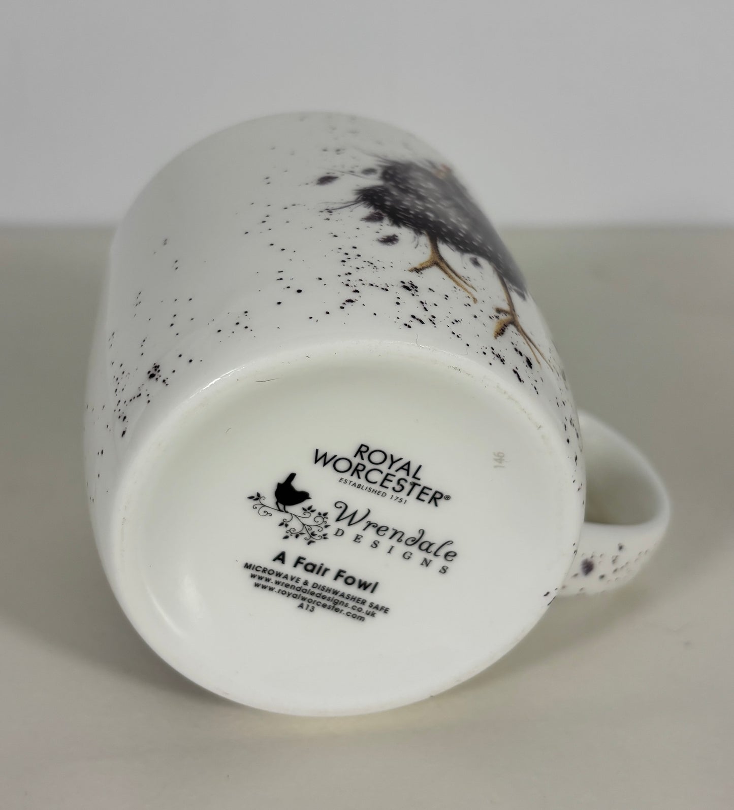 Speckled ceramic mug with a bird design on a white background, featuring Royal Worcester branding.