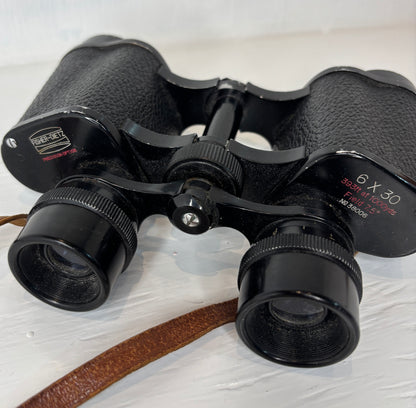 Black binoculars with brand name on a light wooden surface