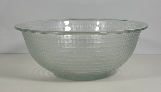 A clear glass mixing bowl with a textured, dimpled grid pattern on a light gray background.