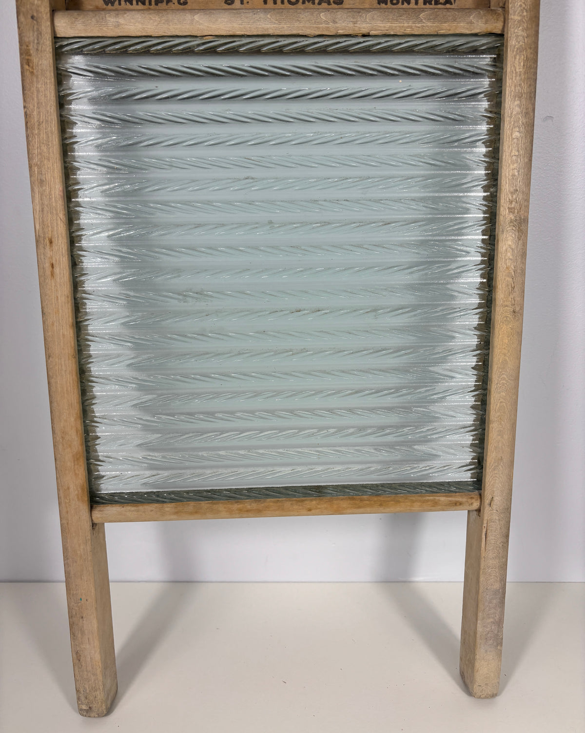 An antique wooden washboard with a ribbed glass panel and a light natural wood frame, photographed against a plain white background.