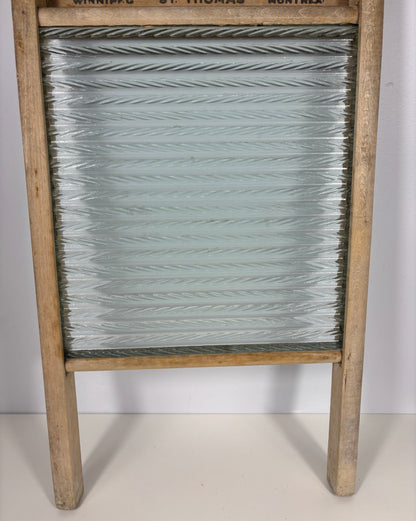 An antique wooden washboard with a ribbed glass panel and a light natural wood frame, photographed against a plain white background.