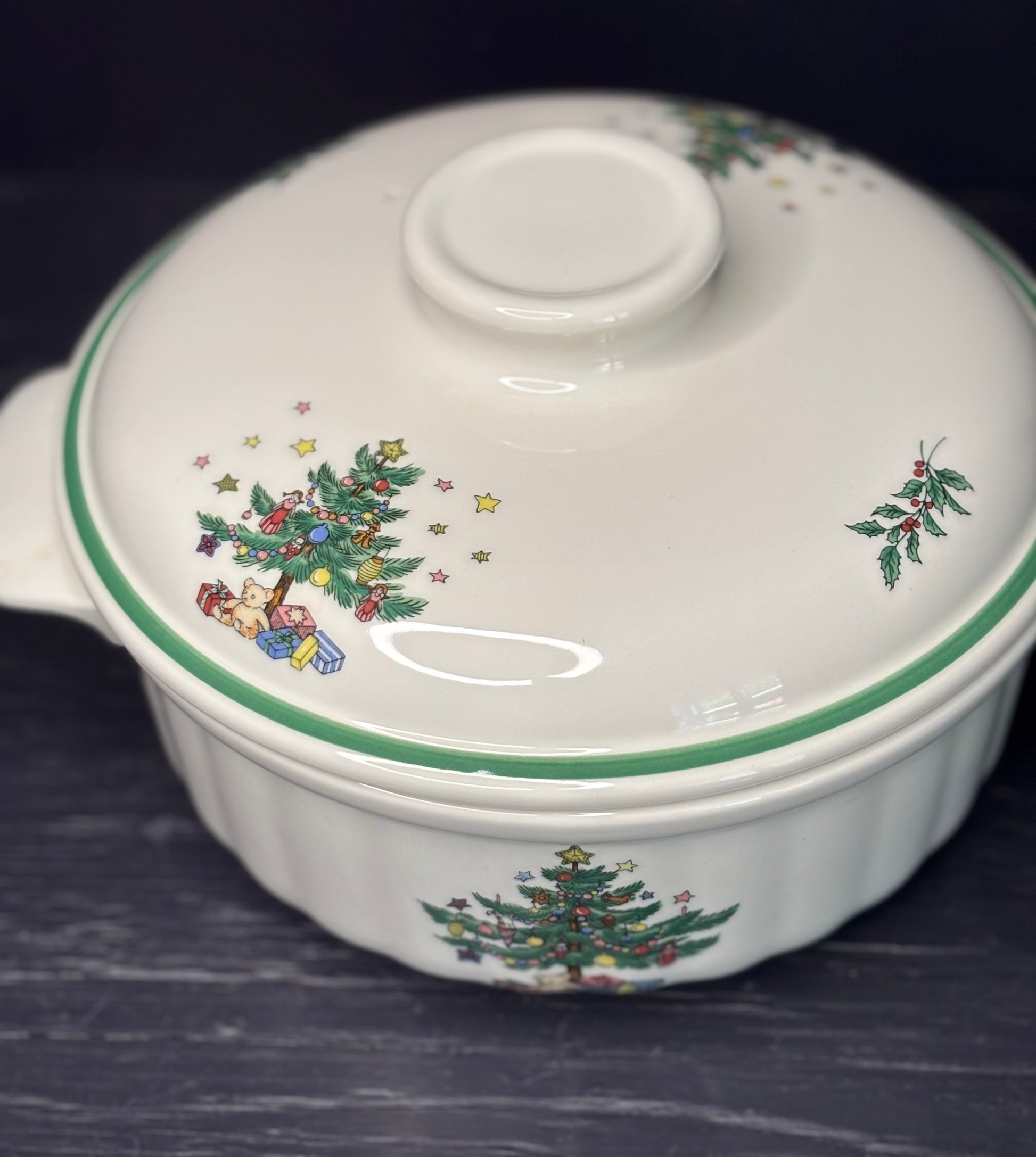Ceramic casserole dish with lid featuring Christmas tree and gift design on a dark background
