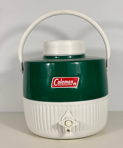 Green and white Coleman cooler with a handle on a light gray background