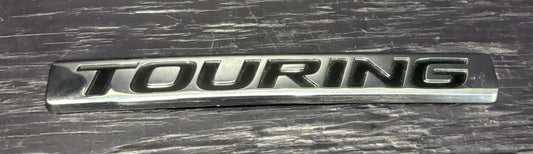 Metallic 'TOURING' emblem on a textured surface