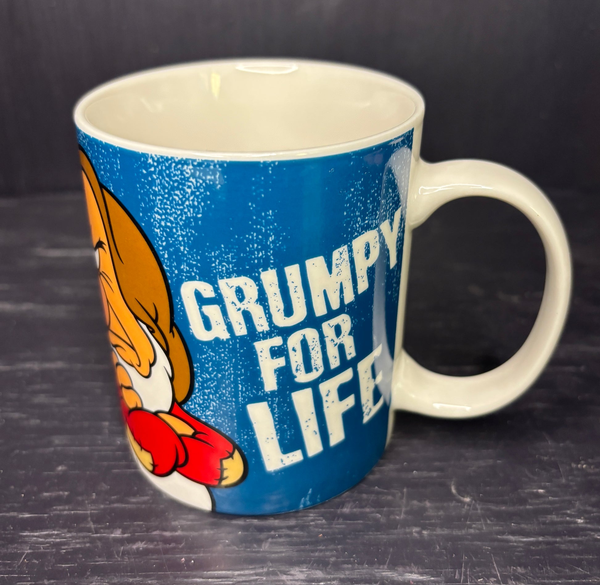 Mug with cartoon character and 'Grumpy for Life' text on a dark surface