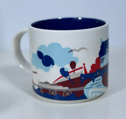 Mug with a colorful design of a boat, buildings, and clouds on a white background