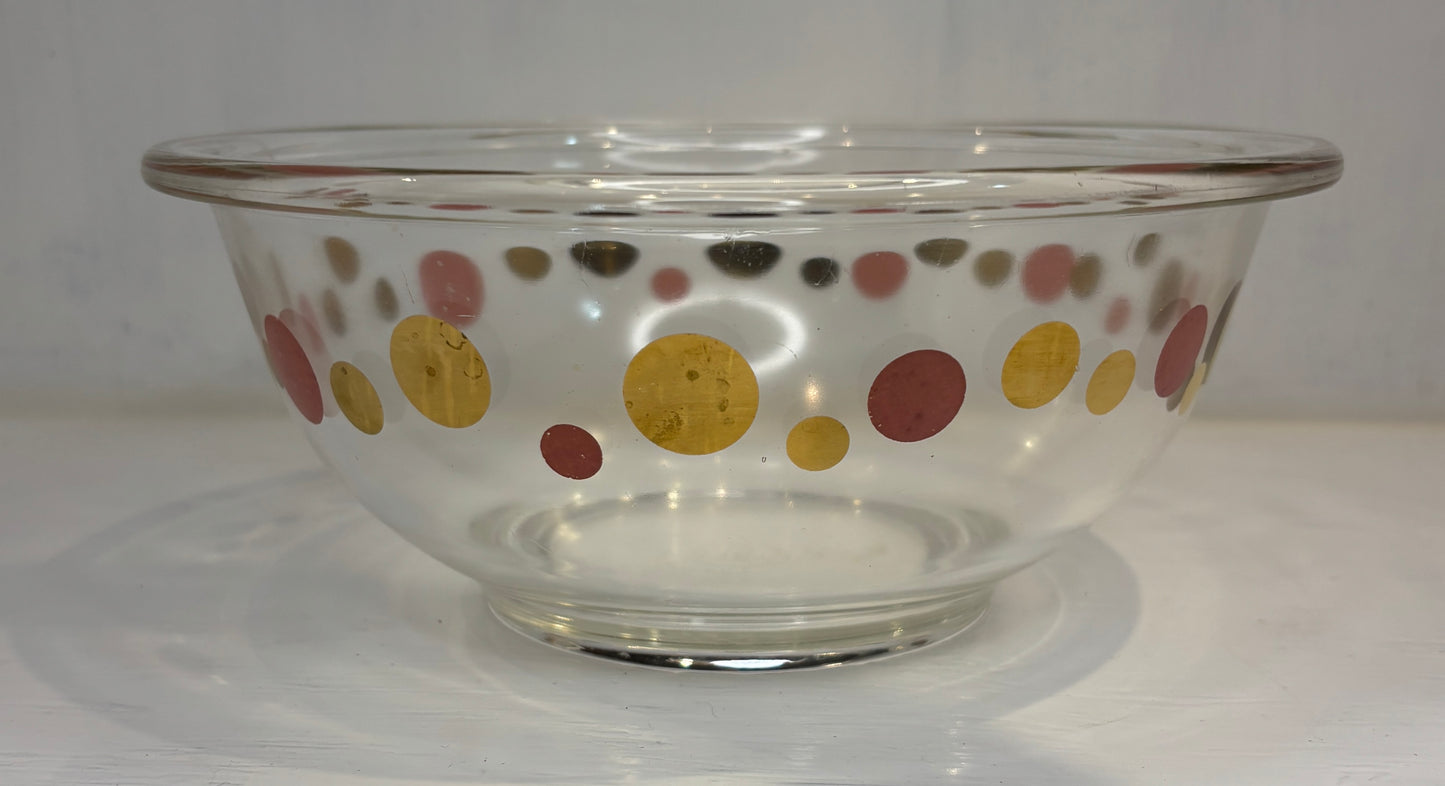 Clear glass bowl with colorful polka dot pattern on a white background