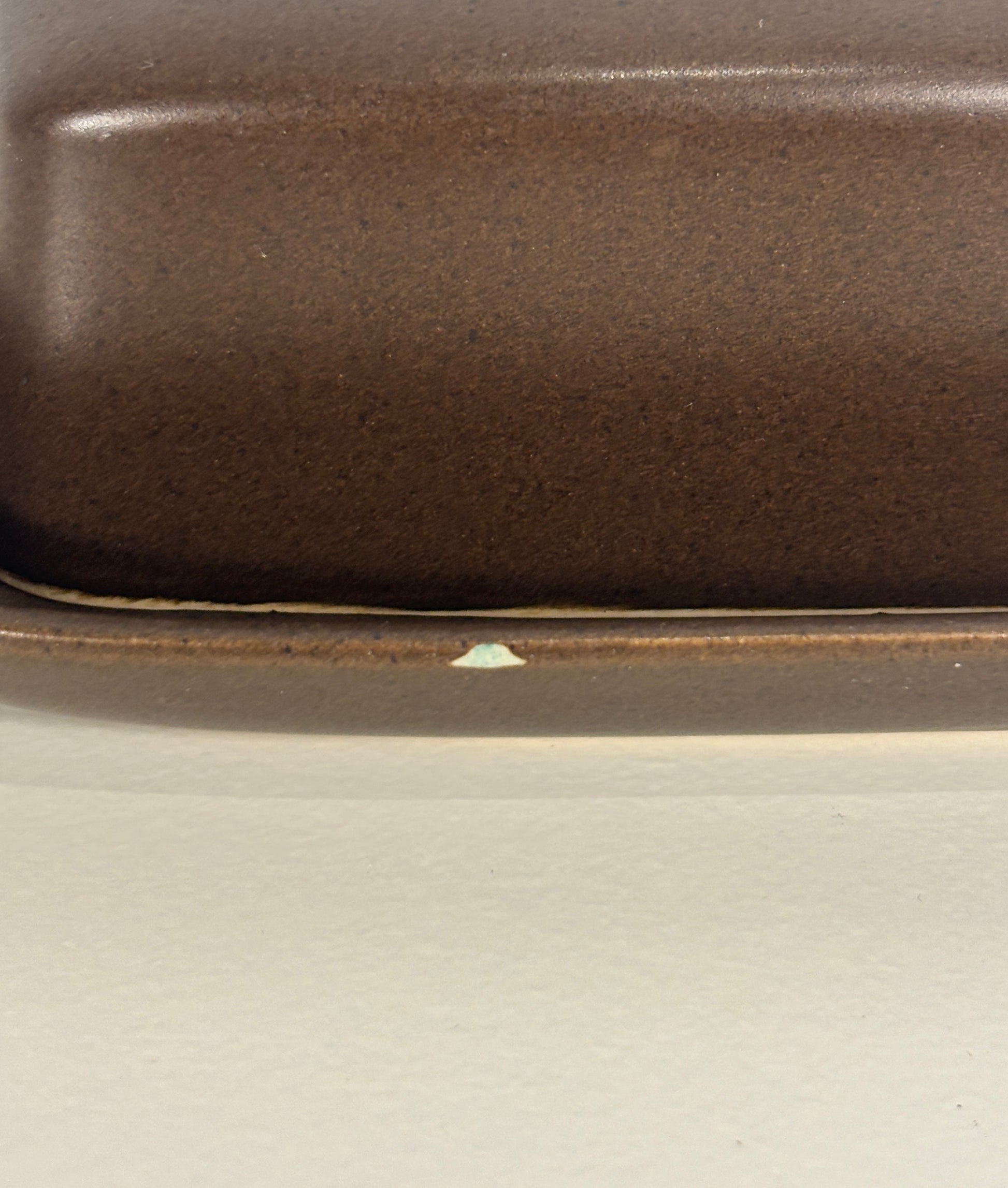 Close-up of a brown ceramic dish on a light gray background