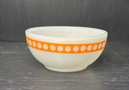 White bowl with an orange band featuring white dots on a dark surface