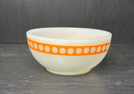 White bowl with an orange band featuring white dots on a dark surface