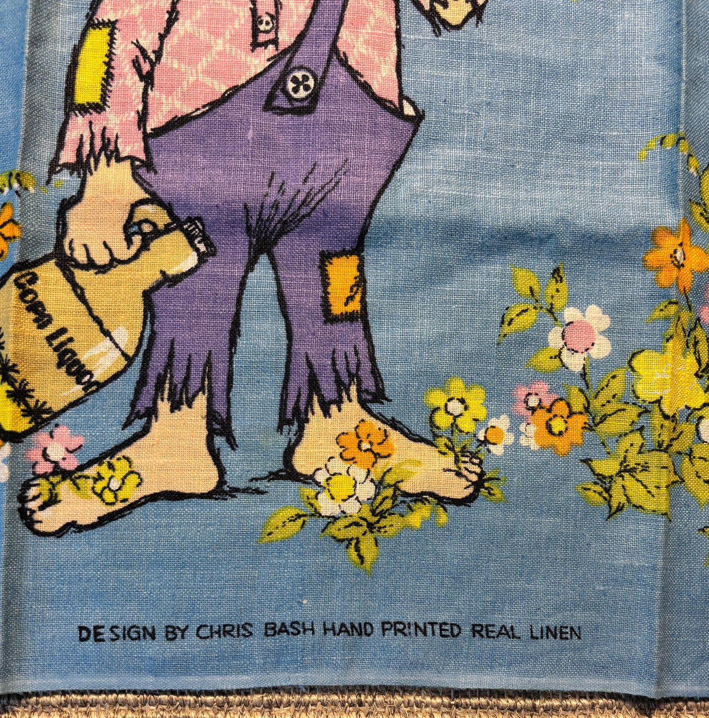 Hand-printed linen fabric with a cartoon character and flowers, designed by Chris Bash.