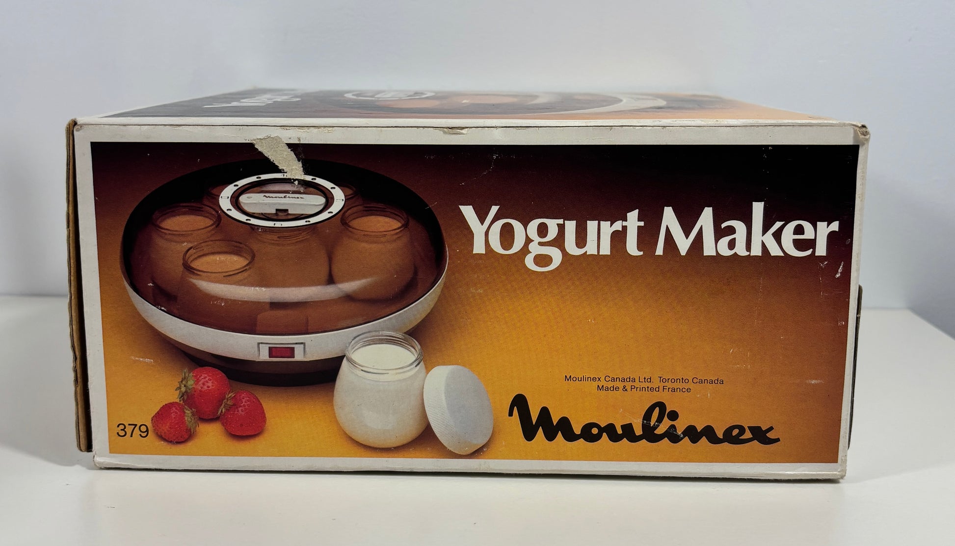 Vintage Moulinex Yogurt Maker retail box, showing the appliance and a small yogurt jar on the front, photographed on a white surface against a white background.