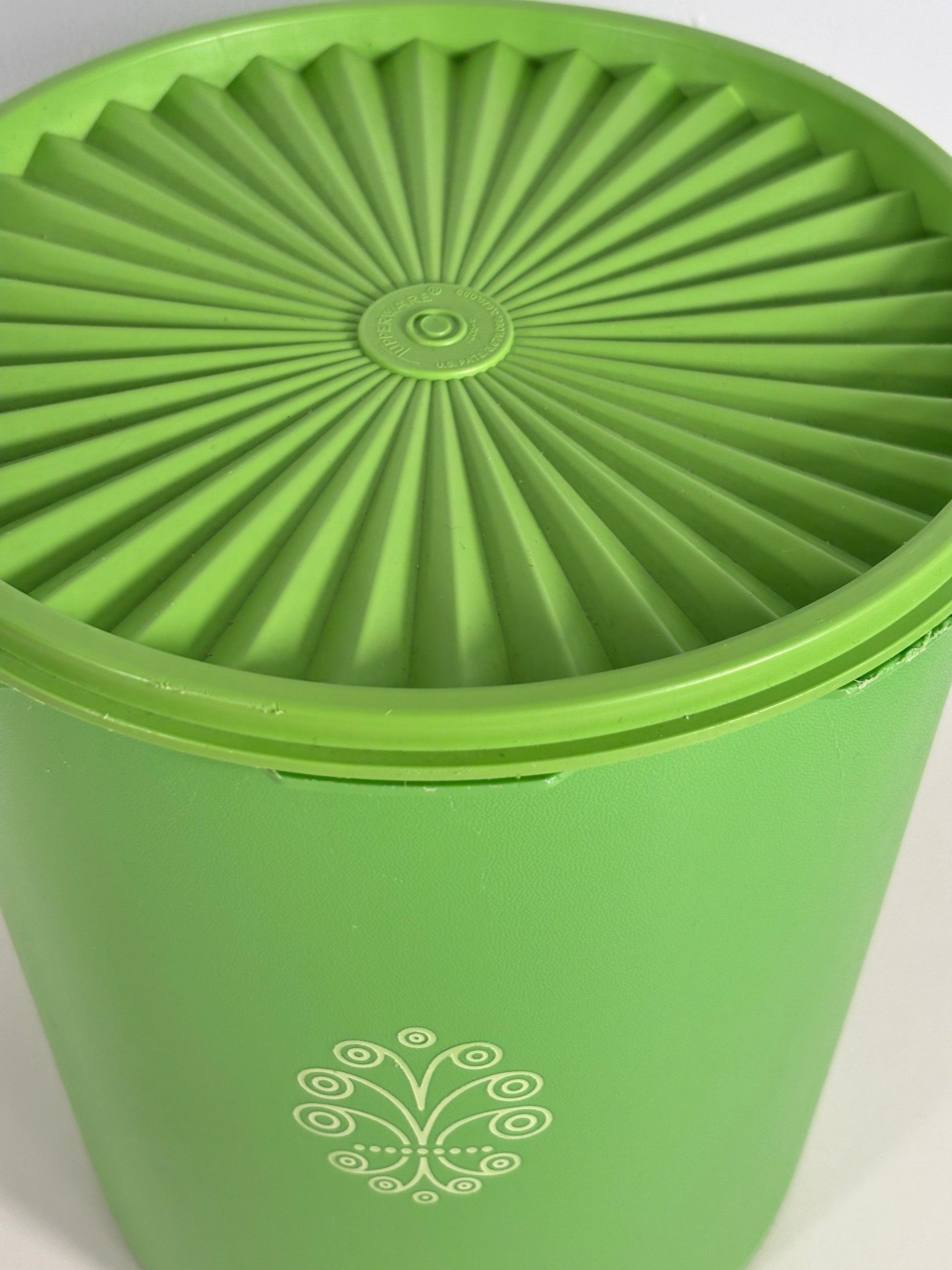 Green plastic container with textured lid on a white background