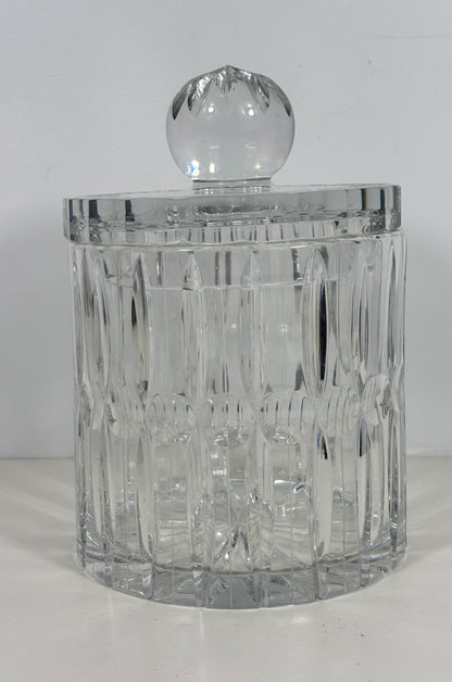 A clear cut-crystal or glass lidded container with a faceted round top, photographed against a plain light background.