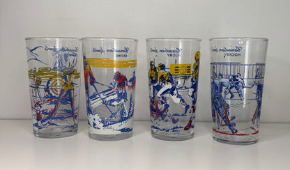 Four glass tumblers with sports-themed designs on a white background