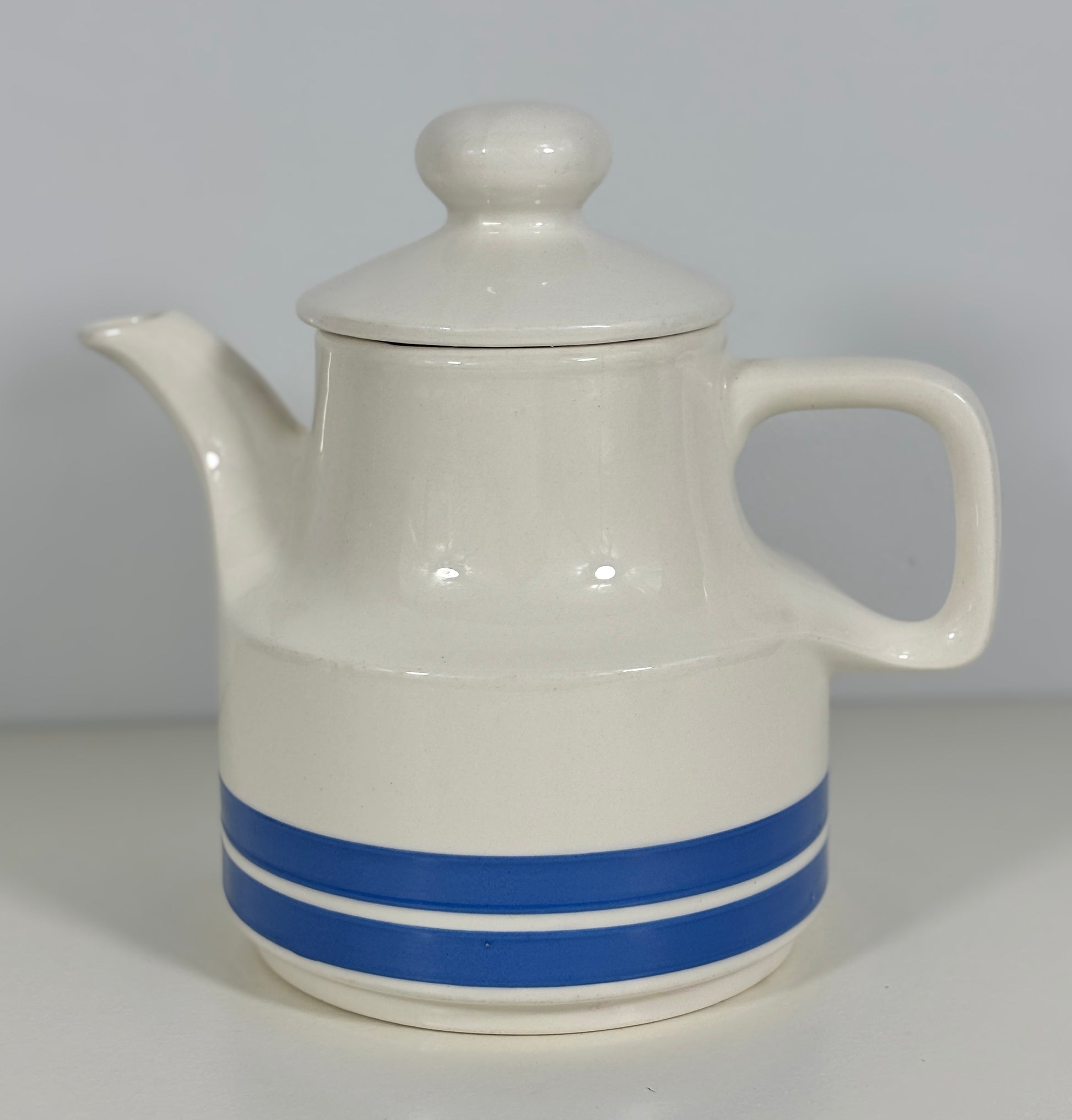 White ceramic teapot with a blue stripe on a white background