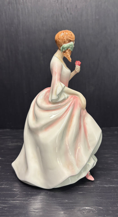 Figurine of a woman in a white dress holding a flower against a dark background