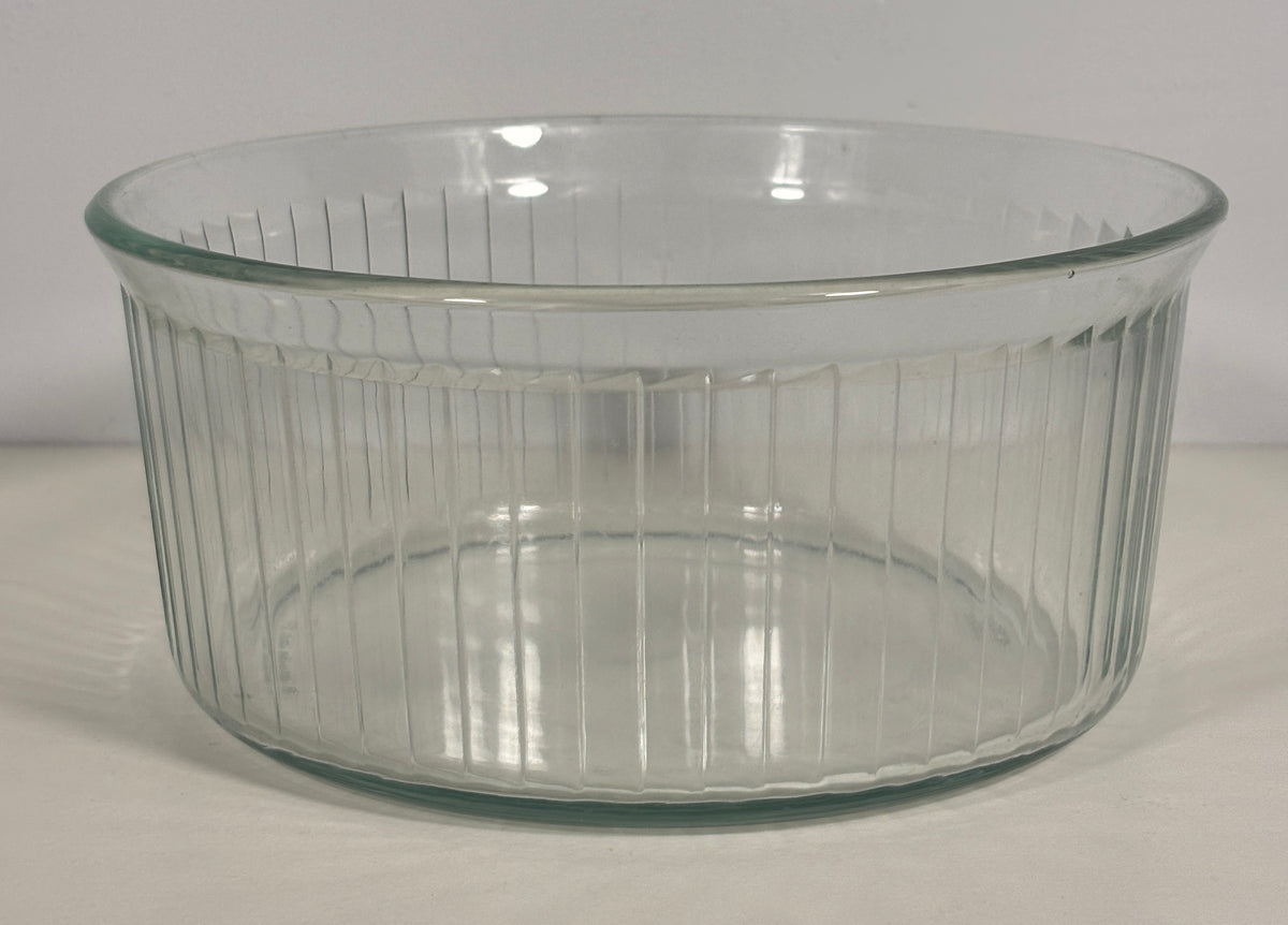 A clear ribbed glass baking dish with a flared rim, photographed on a plain light background.