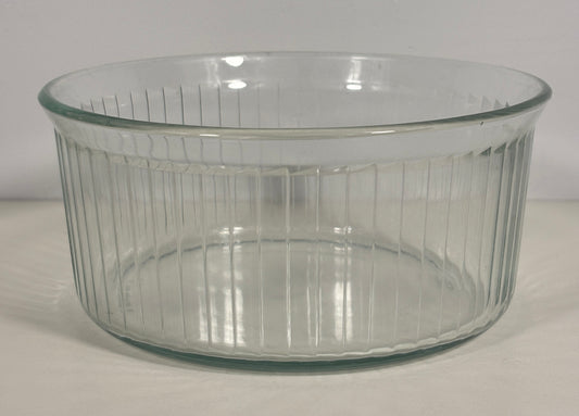 A clear ribbed glass baking dish with a flared rim, photographed on a plain light background.