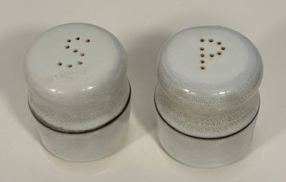 A pair of vintage ceramic shakers with a speckled off-white glaze and dark brown bands, shown on a plain light background.