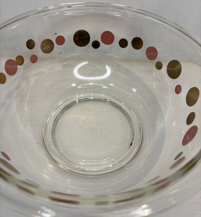 Clear glass bowl with colorful polka dot pattern on a white background