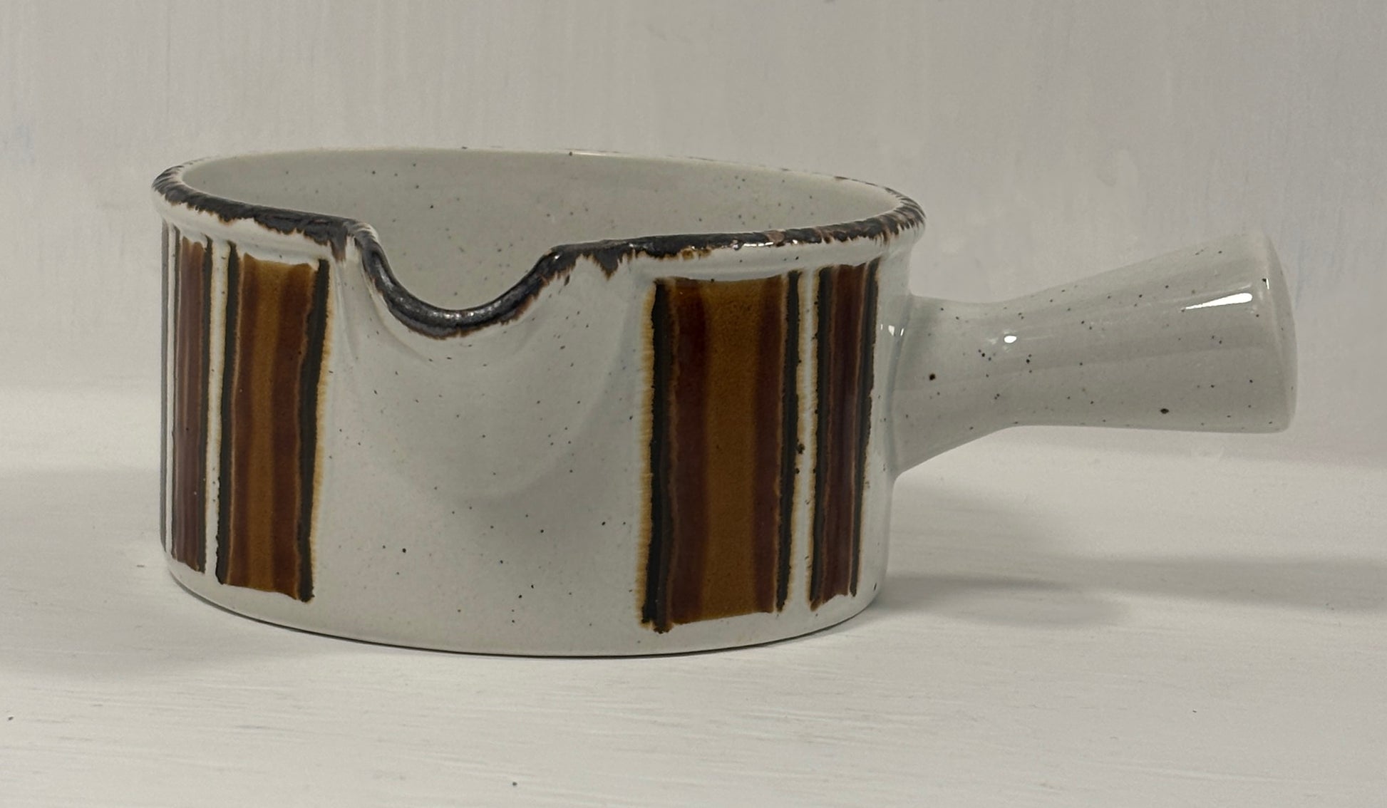 Ceramic gravy boat with brown stripes on a white background