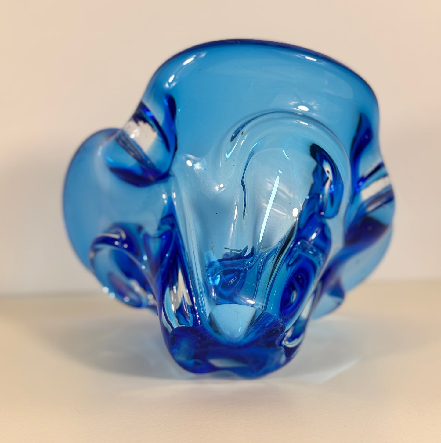 Blue glass ram sculpture on a beige background