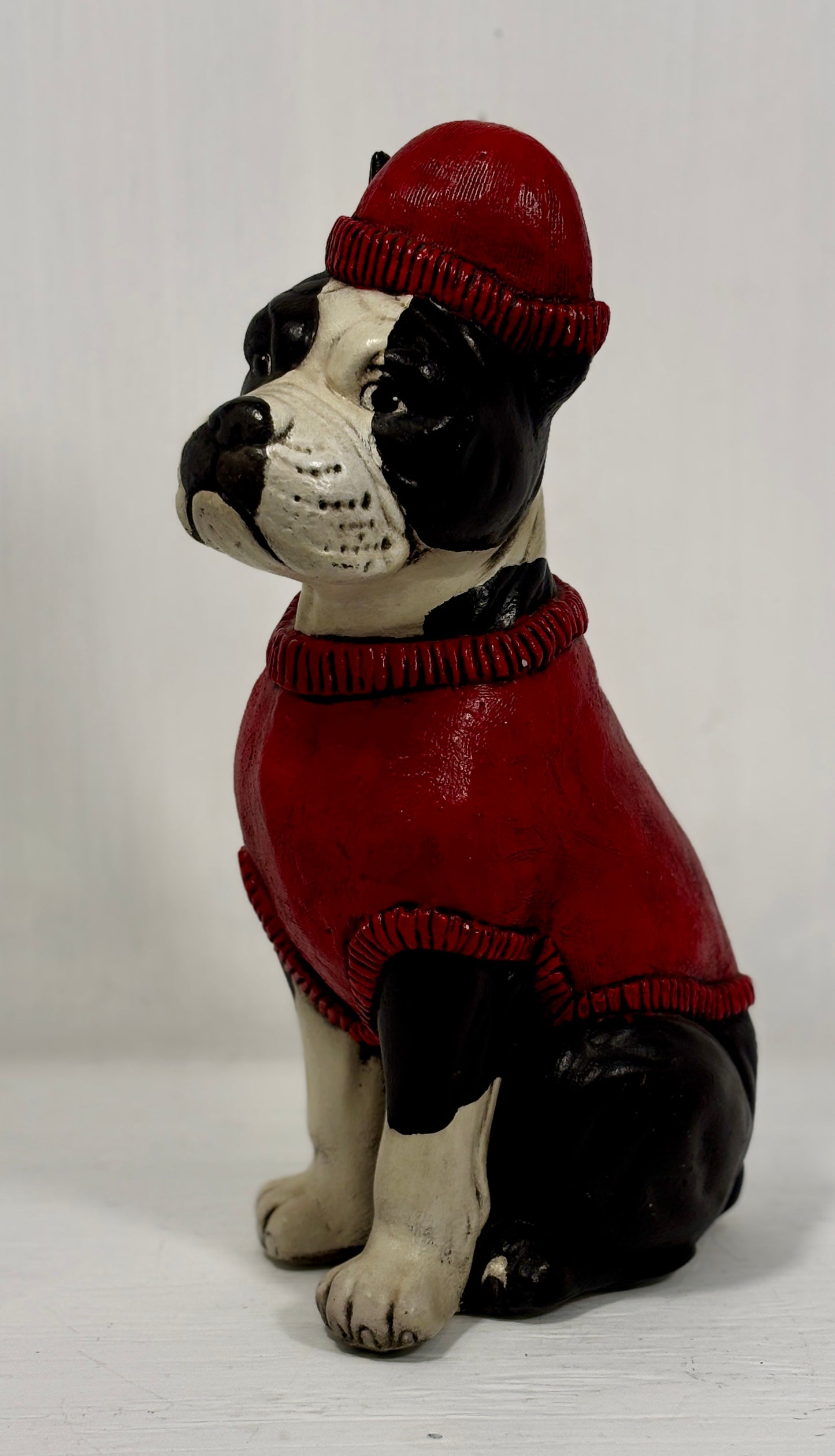 Dog figurine wearing a red sweater and hat on a white background