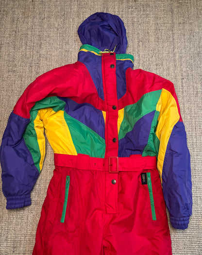 Colorful snowsuit with red, blue, yellow, and green sections on a textured surface.