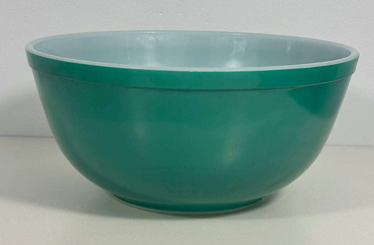 A vintage green glass mixing bowl with a lighter mint-green interior, photographed against a neutral light gray background.