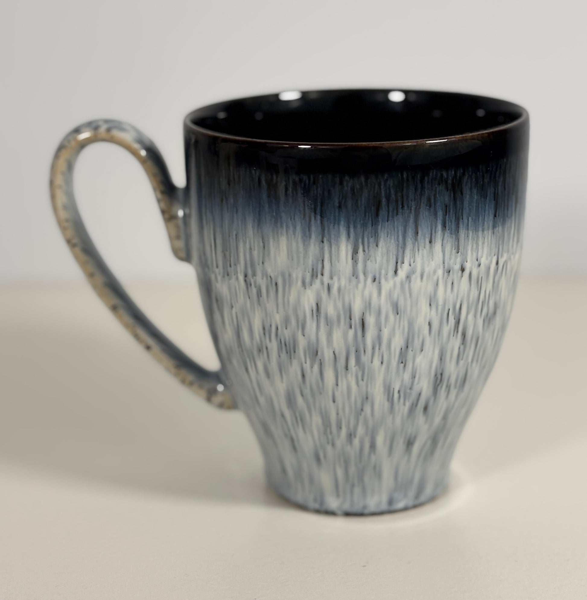 blue and white speckled mug on a light gray background