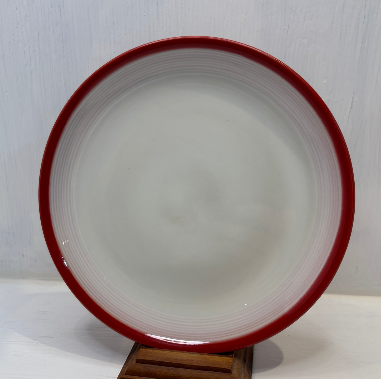 Ceramic plate with red rim on a white background